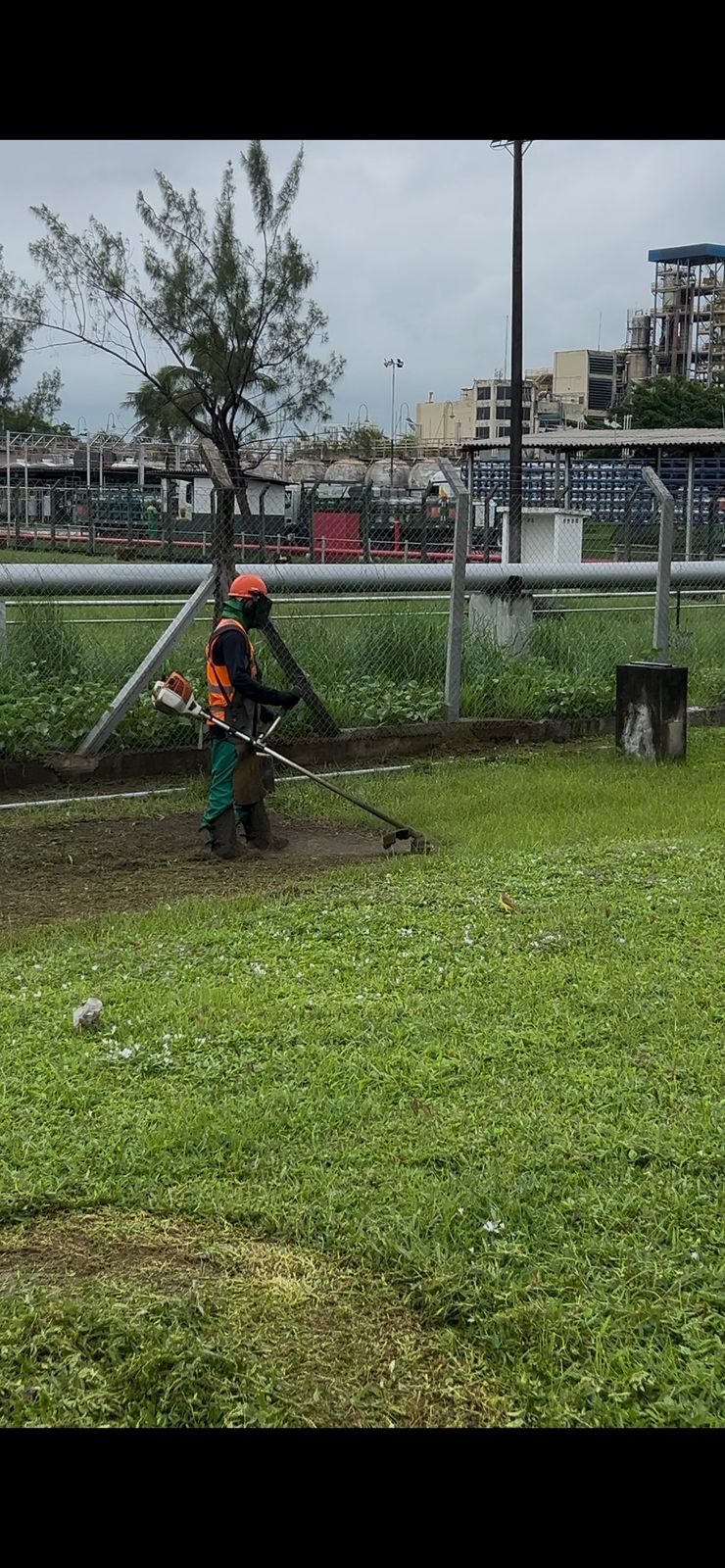Operador realizando roçagem mecanizada em área industrial
